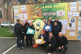 Photo d'un groupe de personnes entourant une mascotte. Une banderole indiquant "La roul'patate" est posée au fond.