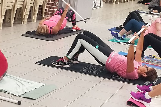 Photo où l'on voit une groupe de personne sur des tapis de fitness, allongées sur le dos en train de faire des exercices.