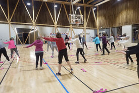 Photo d'un groupe de personnes dans la salle de sport, debout en train de faire des mouvements de bras