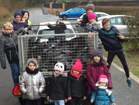 Photo où on voit un groupe d'enfants autour d'une remorque de voiture remplie de sacs poubelle.