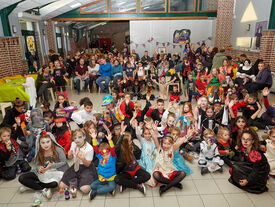 Photo d'un plan très large d'un grand groupe d'enfants, déguisés pour Halloween, dans la salle des fêtes.